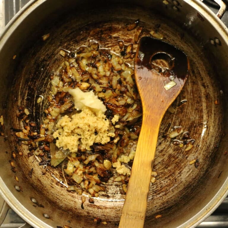 手順 5: カルダモンがプクッとなってきたら、玉ねぎを加えあめ色になるまで強火で炒め、おろしにんにく、おろし生姜を加えます。