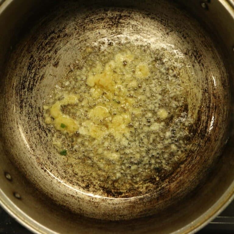 手順 2: 温めたフライパンでサラダ油を熱し、スパイスAを加えます。 シュワシュワしてきたら、にんにく、生姜を加えます。