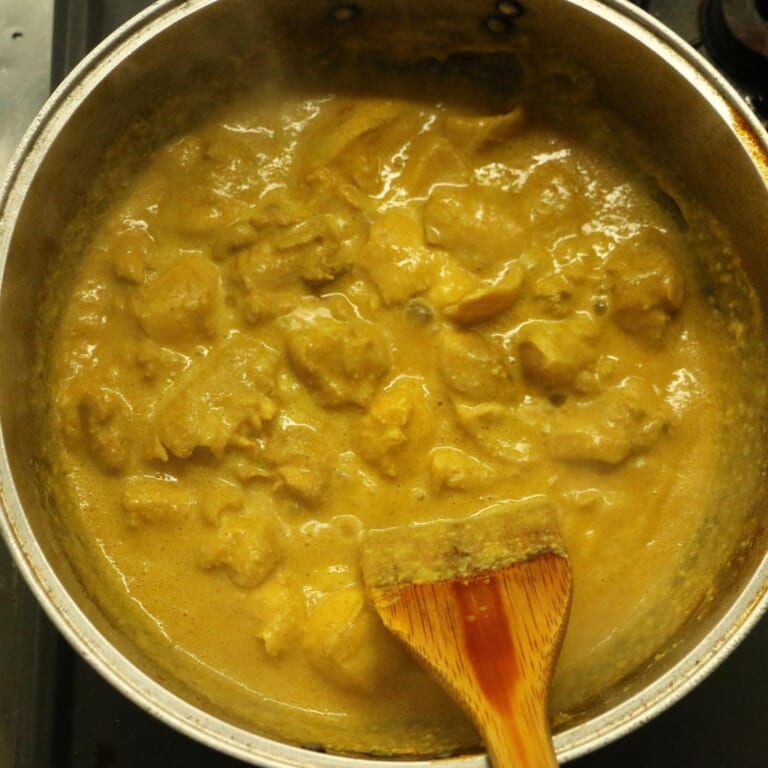 手順 7: トマトを煮込んでいた鍋に新たにサラダ油を引き、マリネした鶏もも肉をマリネ液ごと加えて約15分煮込む。（鶏もも肉に火が通る