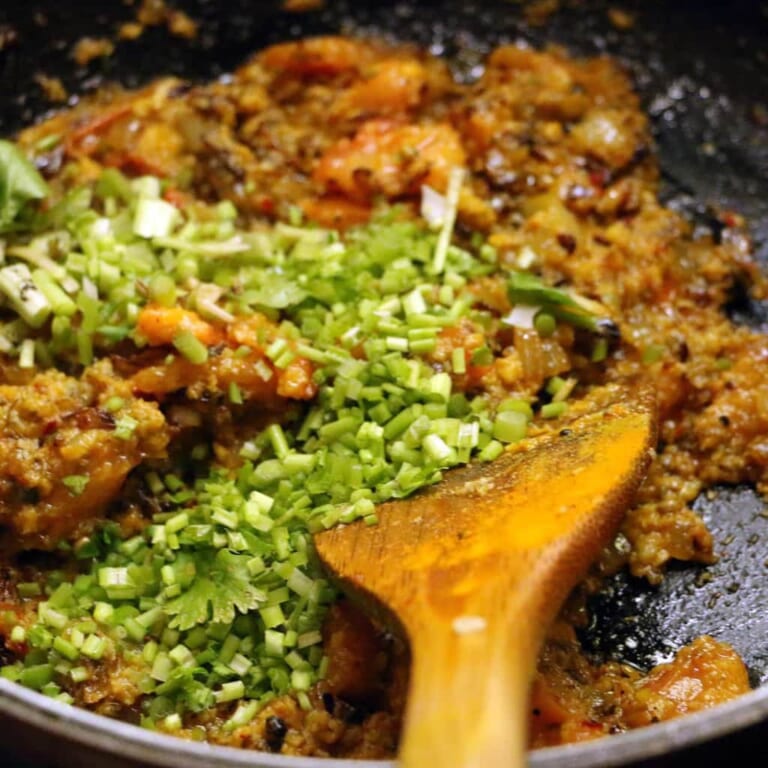 手順 5: ウェットカレーペーストを加えて炒め、油が浮いてきたらパクチーの茎と根を加えます。