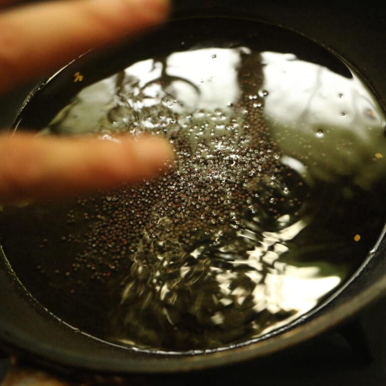手順 6: 別のフライパンに大さじ１杯の油を入れ、マスタードシードをテンパリングします。パチパチと言う音がしたらヒングを加えます。