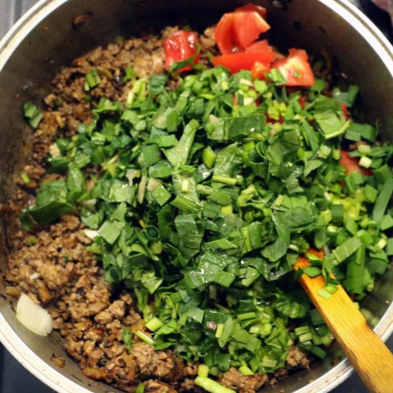 手順 6: 肉にしっかりと火が通ったらトマト、ほうれん草、ニラを加えて軽く炒めます。