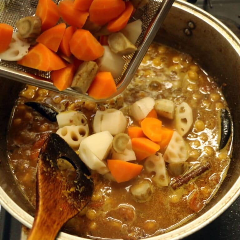 手順 8: ひよこ豆、茹でておいた根菜類を加え、水を加えてふたをして煮込む。ソースがとろりとしてきたらパクチーを加えて混ぜ合わせる。