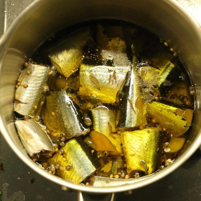 手順 3: 再びスパイスがシュワシュワしてきたら、にんにく、青唐辛子、秋刀魚を入れます。