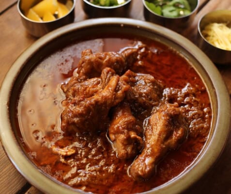 薬味を添えて供される本格チキンカレー、移民が伝えた食文化を映す一皿
