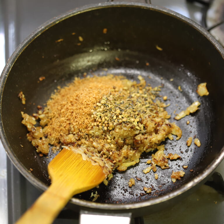 手順 4: にんにく、しょうがを入れて炒め、香りが立ってきたら炒ったスパイスBとココナッツをフライパンに戻して混ぜる。