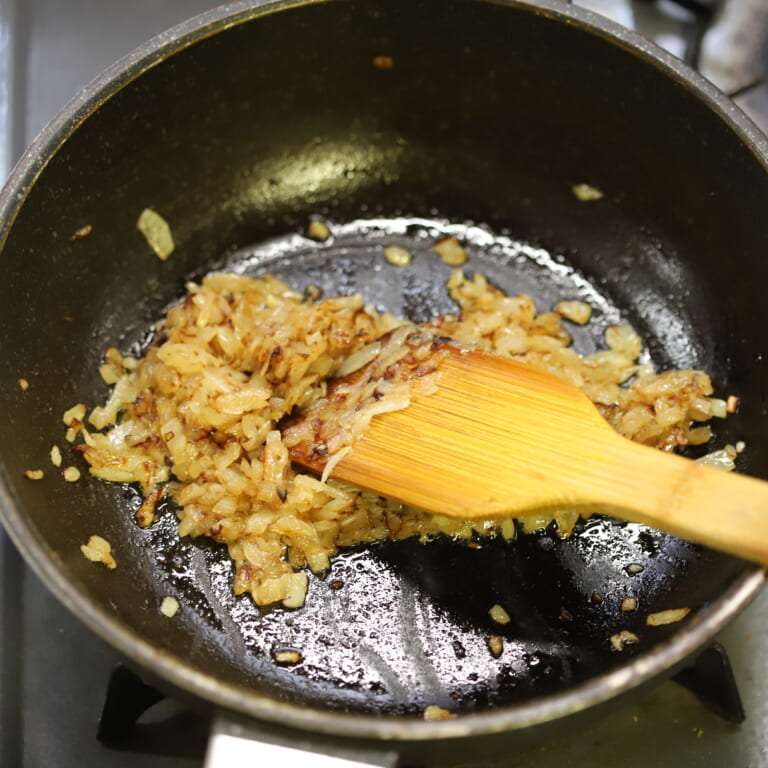 手順 3: あたためたフライパンに油をひき、玉ねぎを加えて表面が飴色になるまで炒める。