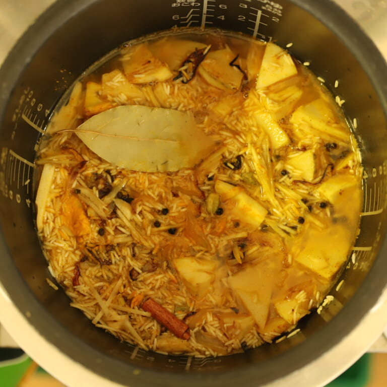 手順 5: フライパンに入っている材料を全て炊飯器に加え、チキンビリヤニブックの「スパイスミックスA」「スパイスミックスB」、生姜、