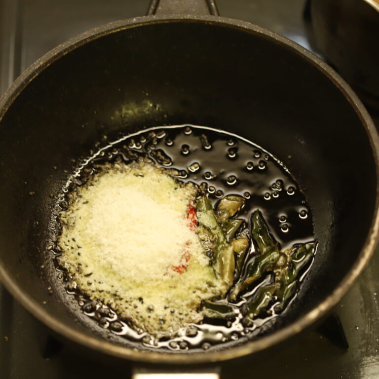 手順 2: 温めたフライパンに油を入れスパイスAのマスタード（ホール）をパチパチさせるまで炒め、火を消しレッドペッパー（ホール）、カ