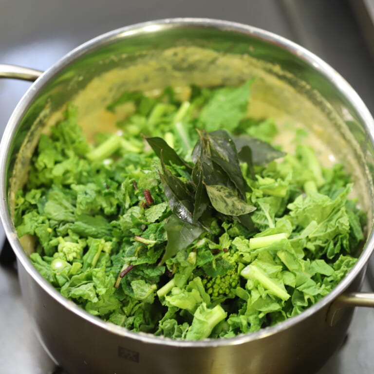 手順 4: 刻んだ菜の花を入れて火が通ったら、ミント、カレーリーフを入れる。