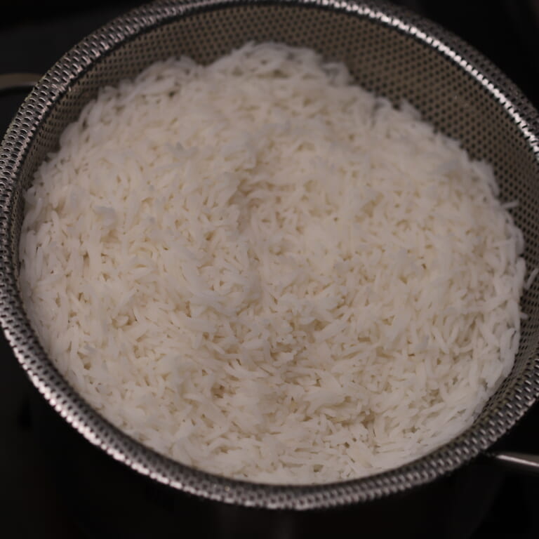 手順 3: 鍋に米茹でる用の水、塩、スパイスC、ギーを加え浸水しておいた米を３、4分芯が少し残るくらいまで茹でてザルなどに上げる。