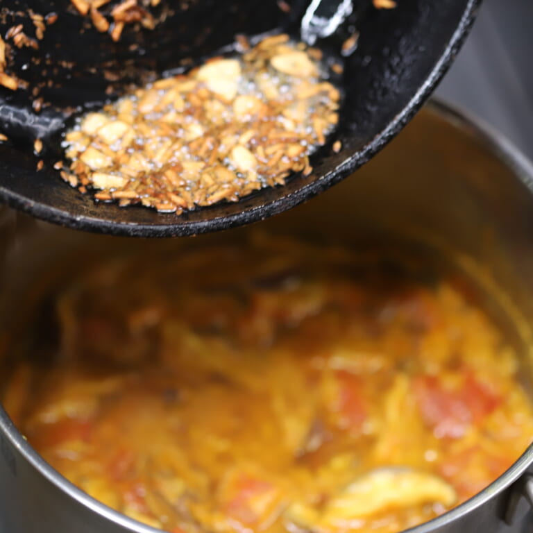 手順 5: 別のフライパンに油を加え温め、にんにく、スパイスCを熱し、油ごと⒋に加える。（テンパリング）