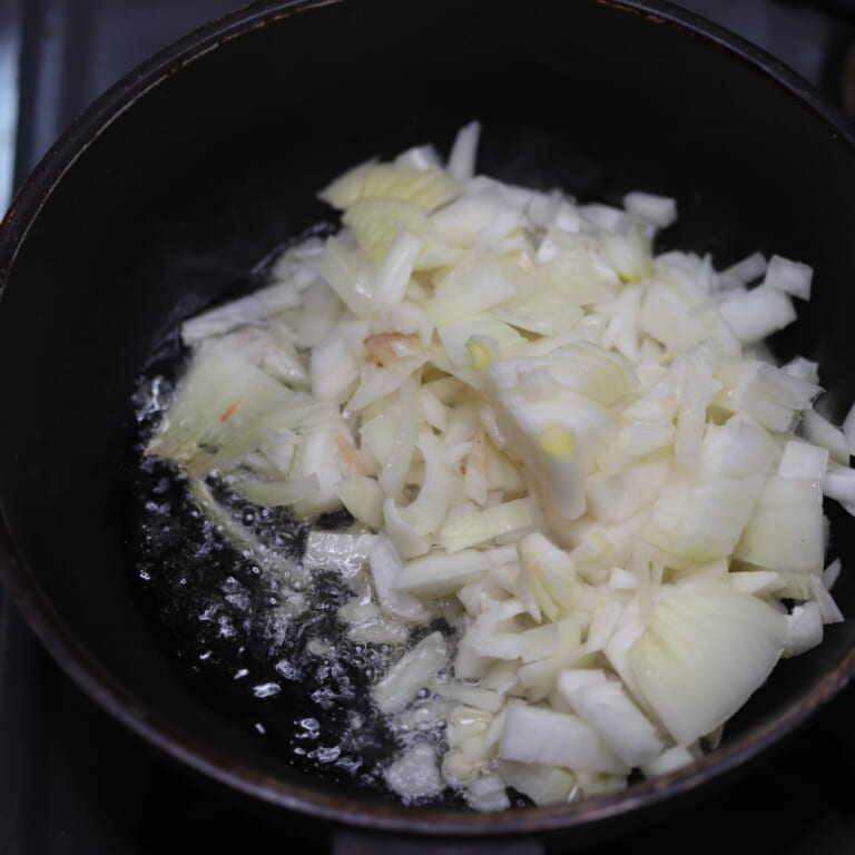 手順 1: 温めたフライパンに油を加え、ヒングを加えてから玉ねぎを炒める。