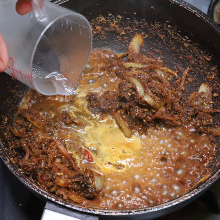 手順 5: ココナッツファインが香ばしくなってきたら水で伸ばし、牛肉を加えなじませる。