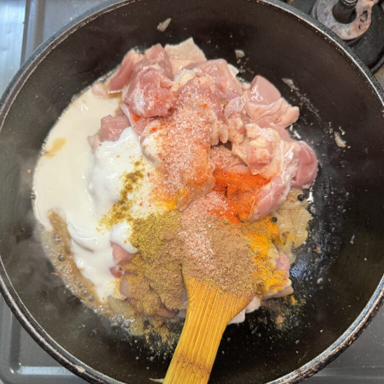 手順 4: 鶏もも肉、おろしにんにく・生姜、ヨーグルト、スパイスB、塩を加え炒め合わせる。