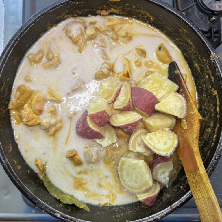手順 5: 鶏もも肉の表面に火が入ったら⒈のペーストを少しずつ加え、一口大に切った1本分のさつまいもも加えグツグツしてきたら火を弱火
