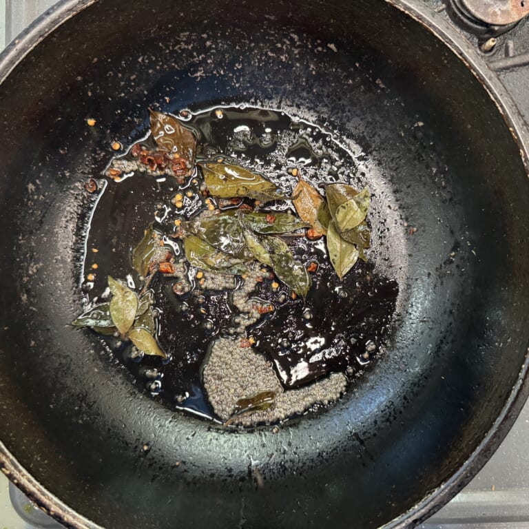 手順 2: 温めたフライパンに油を加えマスタードシード、チリフレーク、カレーリーフを炒める。