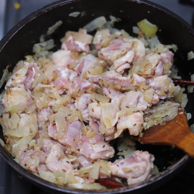 手順 3: 玉ねぎがほんのり色づいたらすりおろしにんにく、生姜、鶏もも肉を加えて炒める。