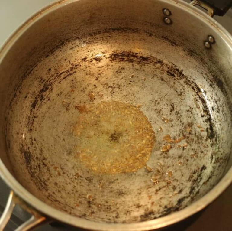 手順 2: フライパンに油をひき、クミン（ホール）を入れ、弱火で香りが立ってくるまで炒める。