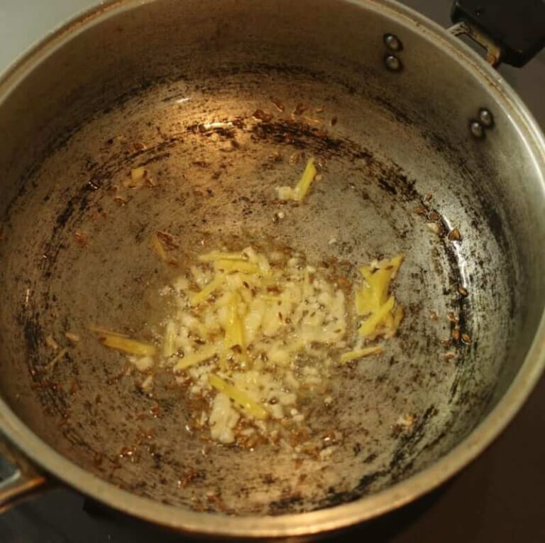 手順 3: 香りが出てきたらにんにくと、千切りにしたショウガの半分（残りの半分は後ほど使用）を加える。