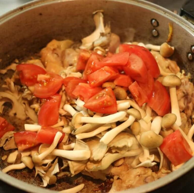 手順 4: 鶏もも肉を加え、色が変わるまで炒めたらキノコ類とトマトを加える。