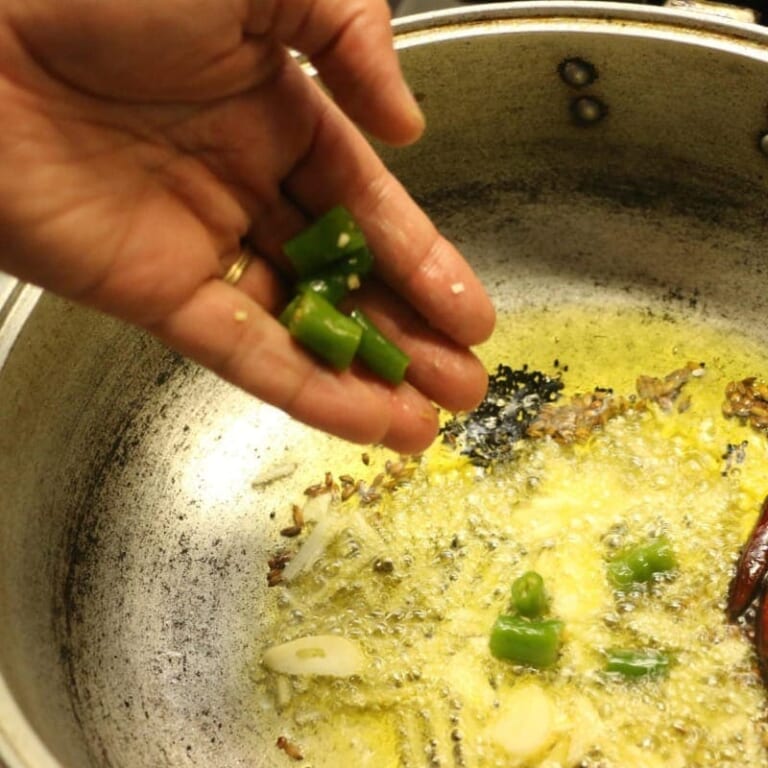 手順 4: パチパチと音がしてきたら、を止めにんにく、青唐辛子、塩の順に加えながら油の熱を冷まします。