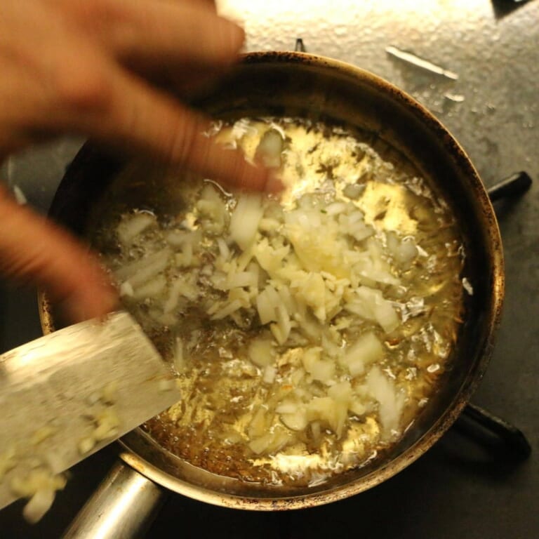 手順 4: 別に小さめなフライパンを温め、 油を入れスパイスA、にんにく、玉ねぎを火にかけ香りをたたせる。 （テンパリング）
