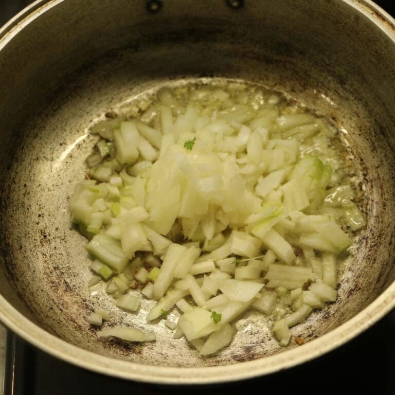 手順 2: 温めたフライパンに油とクミン（ホール）を入れます。シュワシュワとしてきたら玉ねぎを加えて飴色になるまで炒めます。