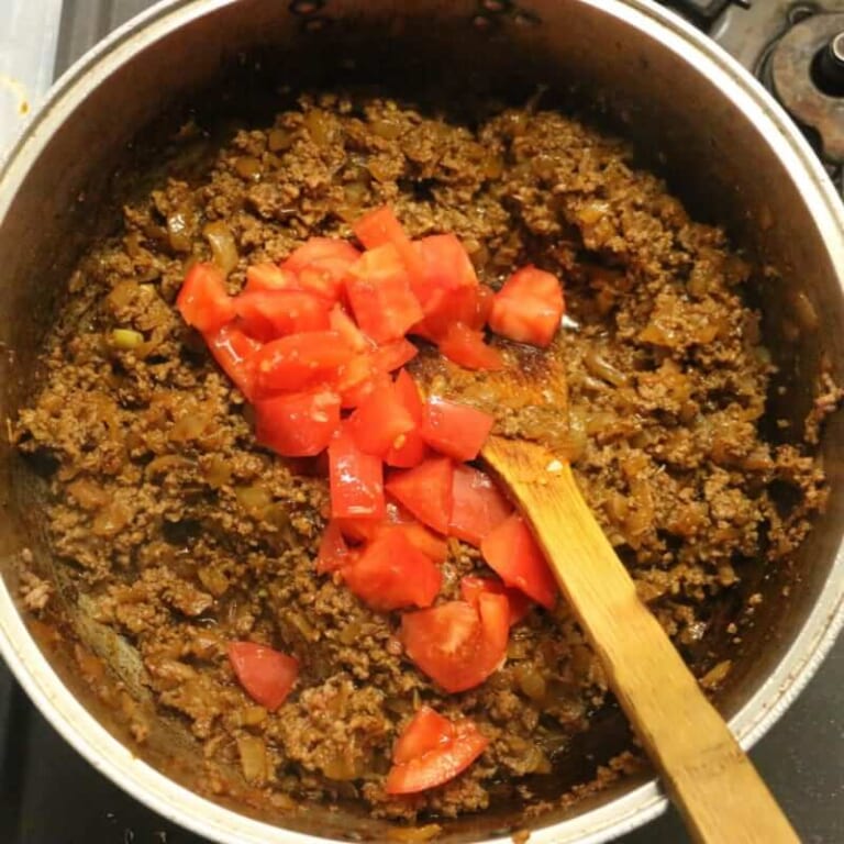 手順 5: トマトを加え炒め合わせ、カレーフレークと水を加え蓋をする。