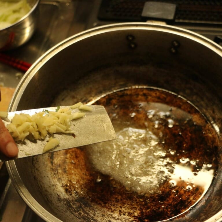 手順 1: 温めたフライパンに油を入れスパイスAを加えシュワシュワとしてきたらにんにく、玉ねぎを加え炒める。