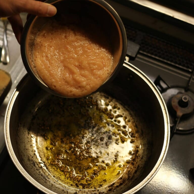 手順 4: パチパチと音がしてきたらペーストにしておいた玉ねぎとトマトを加え炒める。