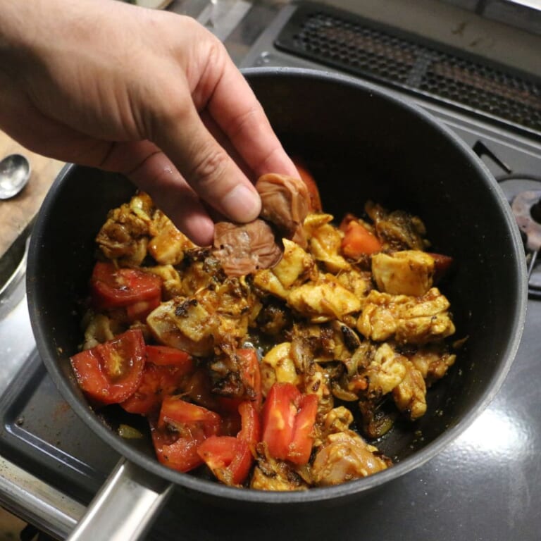 手順 4: 鶏もも肉の表面に火が入ったらトマトと種を取った梅、カレーリーフを加え軽く炒め合わせる。
