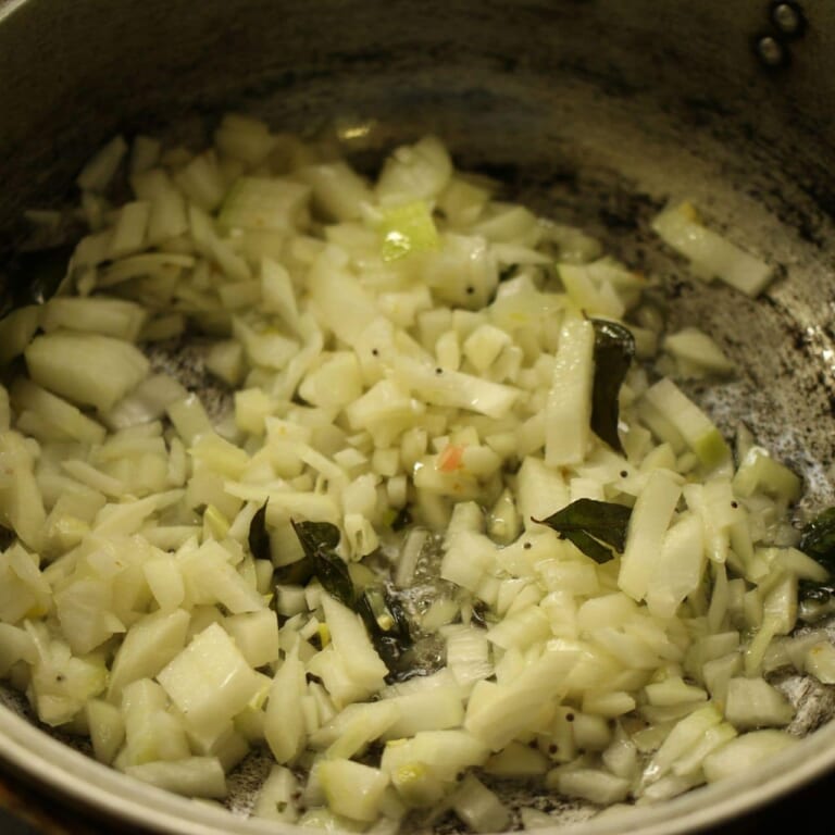 手順 3: 温めたフライパンに油とスパイスB、カレーリーフを加える。パチパチしてきたら玉ねぎを加え、飴色になるまで炒める。その後おろ