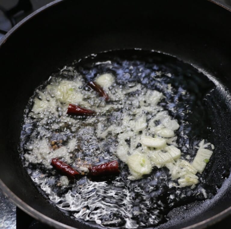手順 6: 別のフライパンに油を入れスパイスA、にんにくをテンパリングする。