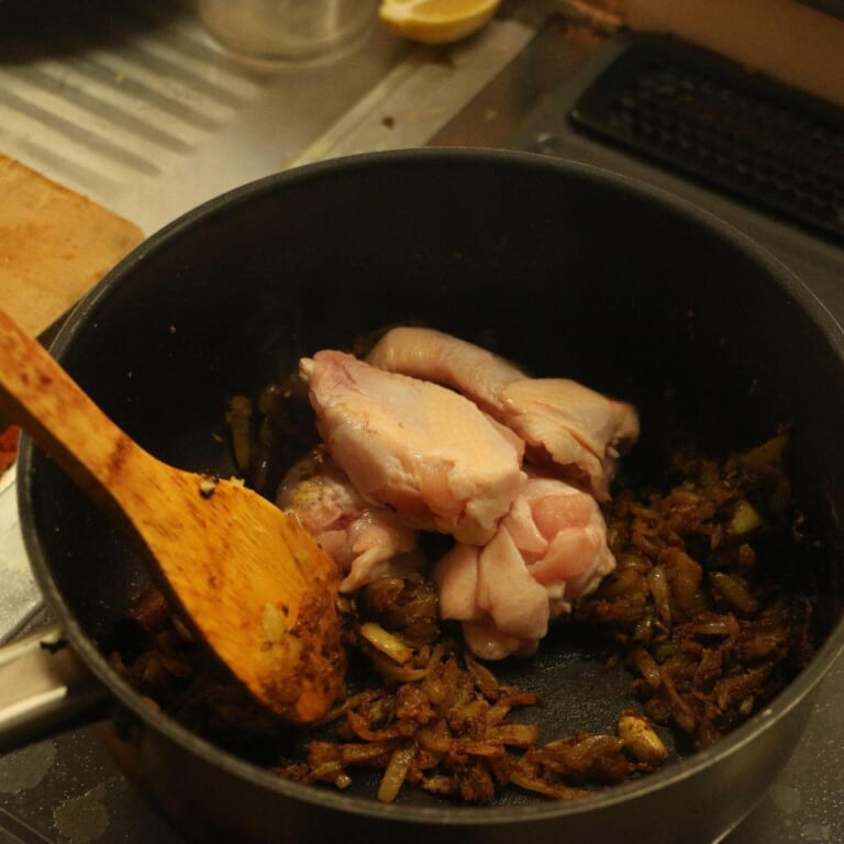 手順 3: スパイスBと塩を加え炒め合わせ鶏肉(手羽元)を加え炒める。