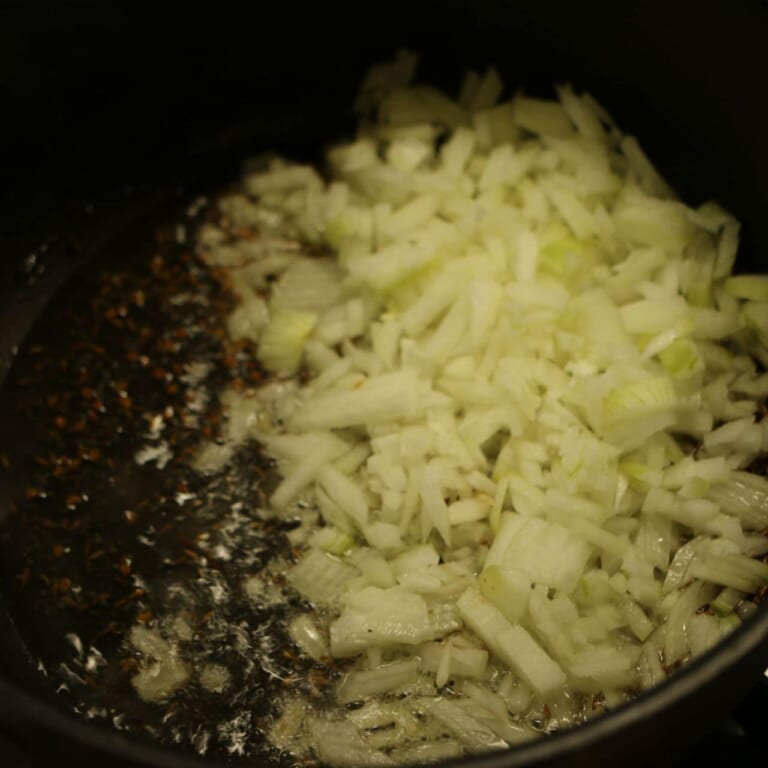 手順 3: 煮込んでいる間に鍋に油、スパイスAを加え、香りが立ってきたら玉ねぎを炒める。