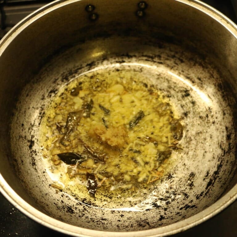 手順 3: フライパンを温め油を入れスパイスA（マスタードシード、カレーリーフ）を加えて香りを立たせる。香りが立ってきたらにんにく、
