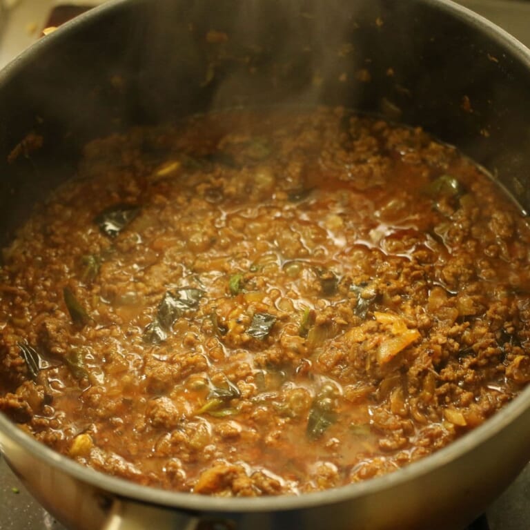 手順 7: 煮込んだカレーと、チャートマサラナッツやパクチー、レモンなどを盛り付ける。食べるときは是非レモンを絞りかけて。