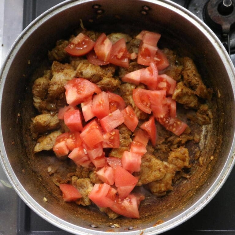 手順 5: 豚肉を加え軽く炒め合わせトマト、ヴィネガーを加え炒め合わせてから水を少しずつ加える。