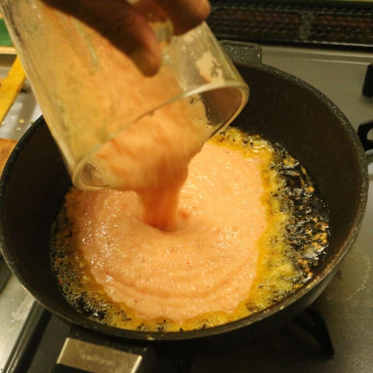 手順 4: パチパチと音がしてきたらペーストにしておいた玉ねぎ、トマトを加える。