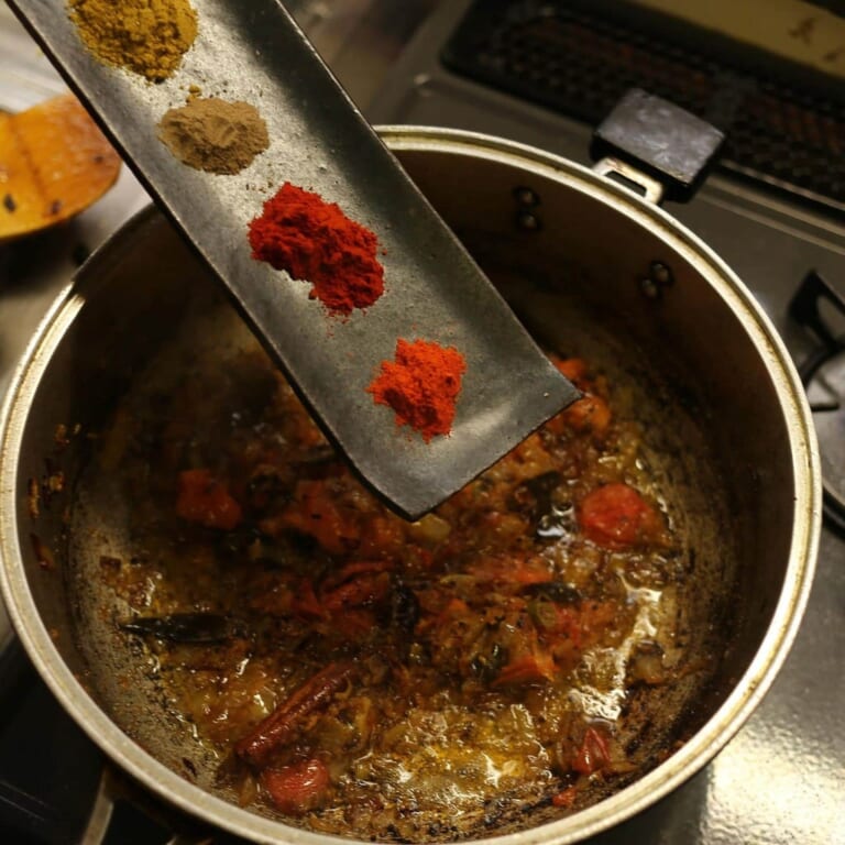 手順 5: 香りがたってきたらトマトを加え、水分が飛ぶまでしっかり炒めたらスパイスBと塩を加えます。