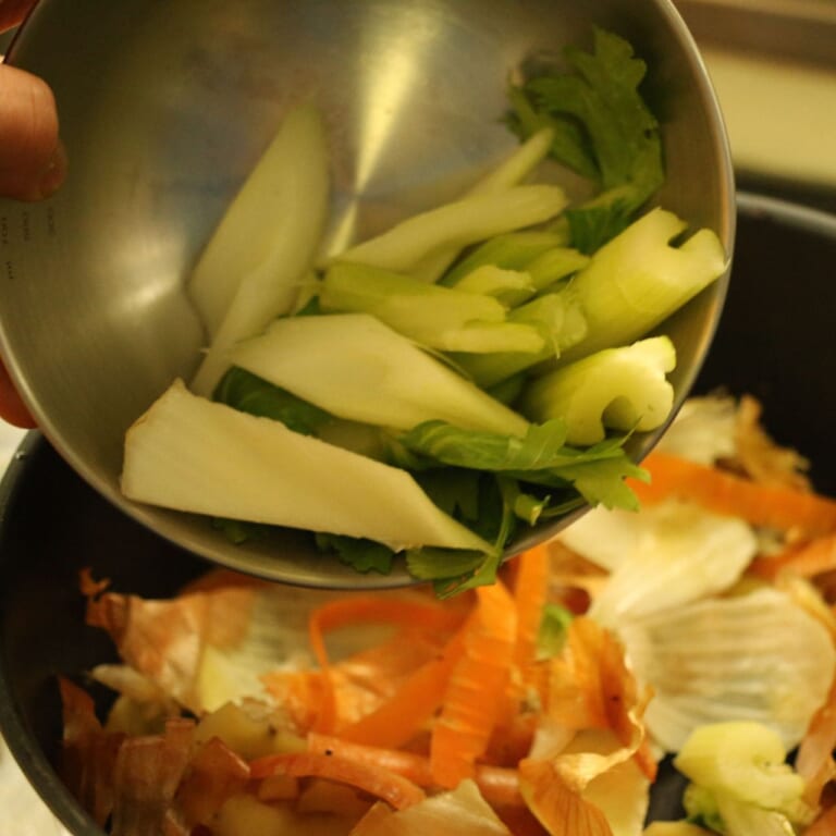 手順 2: フライパンの手羽元を取り出し、同じフライパンに野菜のヘタや皮、セロリを加え香りが経つまで炒めたら、水を加えていき煮込んで