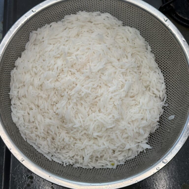 手順 3: 茹でた米をザルにあけておく。