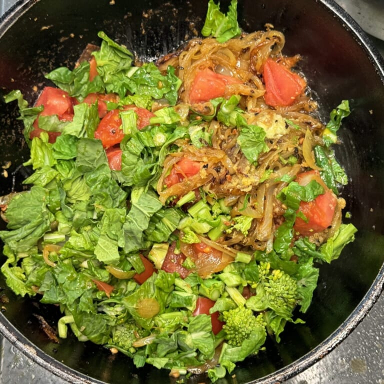 手順 3: 玉ねぎ、トマト、おろしにんにく、生姜、菜の花の茎の部分の順に加える。