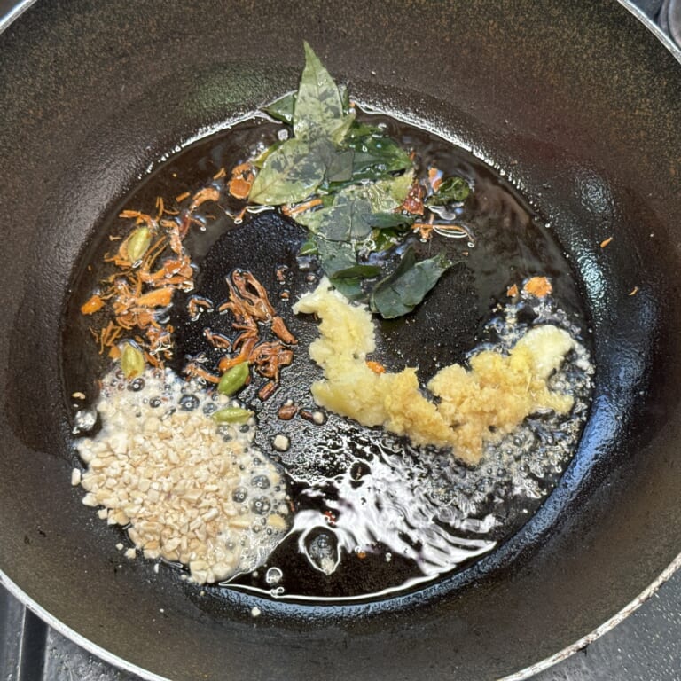 手順 5: カルダモンがぷくっとなってきたらにんにく、生姜を加えカシューナッツ、生姜の千切り、カレーリーフを炒め合わせる。