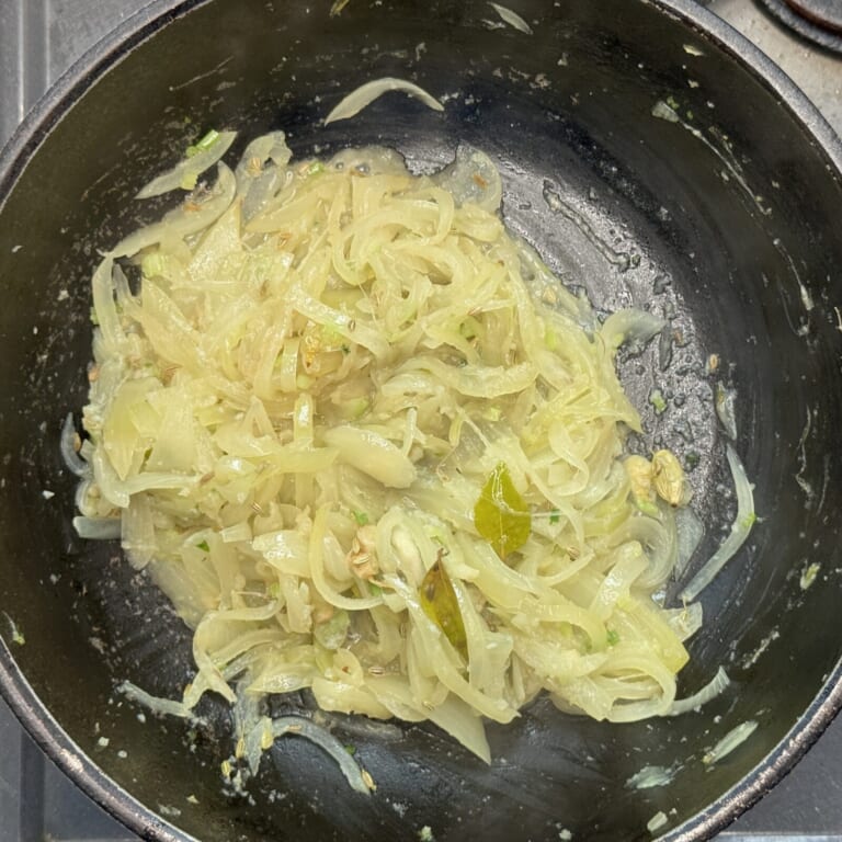 手順 3: 水分が飛んだらスパイスA、油、おろしにんにく、生姜、塩を加え、ざく切りにしたパクチーの茎と根の部分を加え炒め合わせる。
