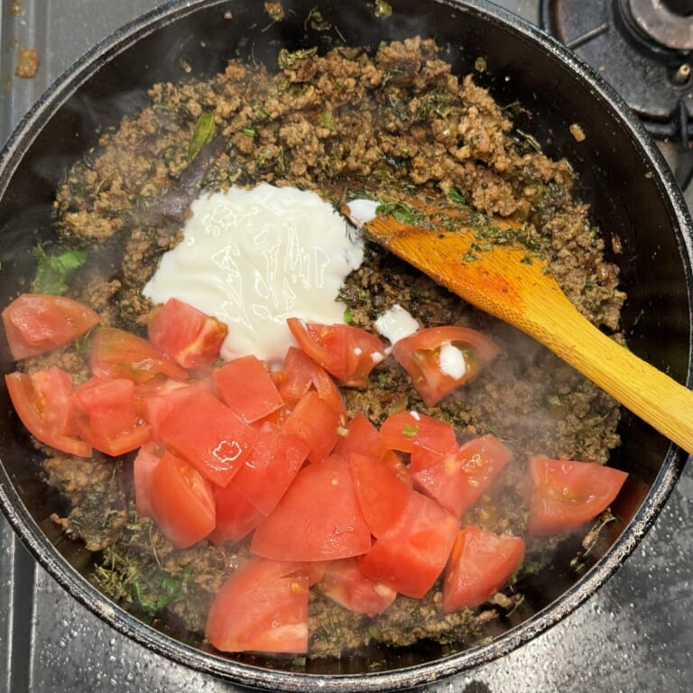 手順 4: 合いびき肉を加えしっかりと火が通ったらトマト、ヨーグルトを加え炒め合わせる。油が浮いてきたら水を加えて煮込む。