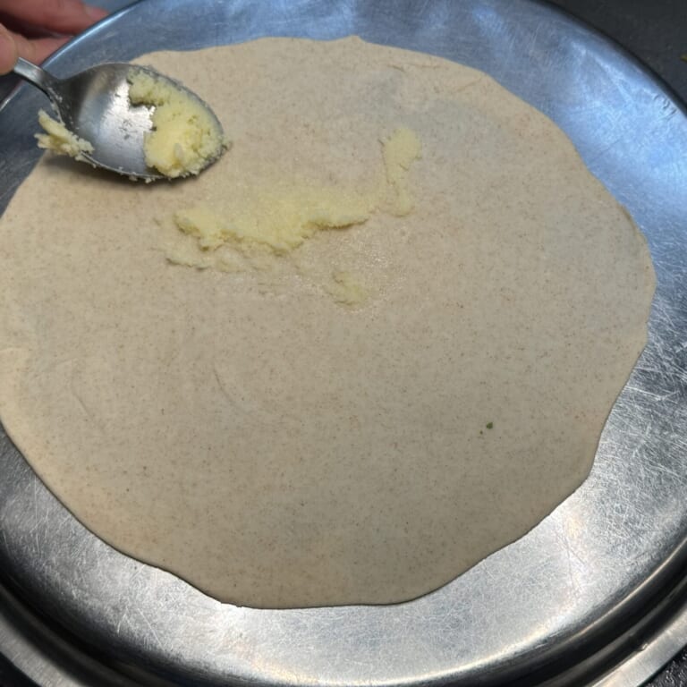 手順 3: 分けた生地を麺棒などで薄く伸ばし、ギーを全体に塗る。