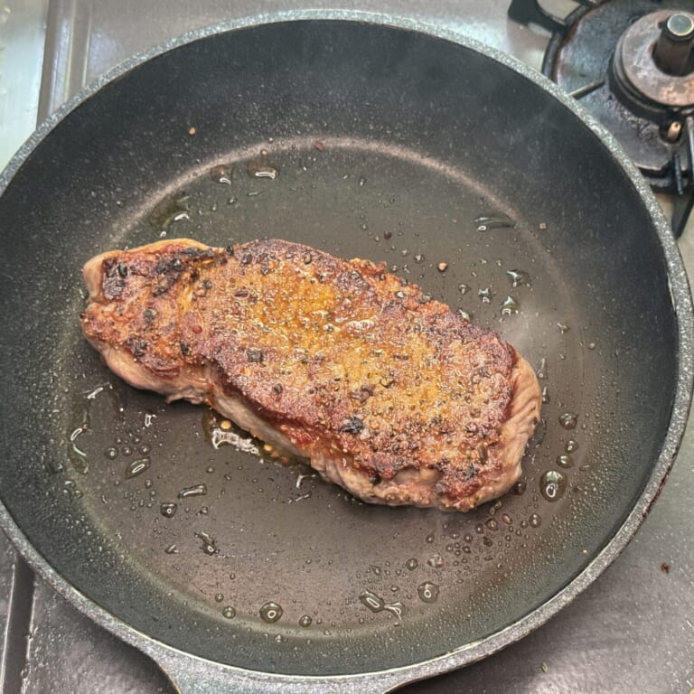 手順 2: フライパンに油を引き、煙が出るぐらいまで熱し、ステーキ肉を片面1分半ずつ焼く。