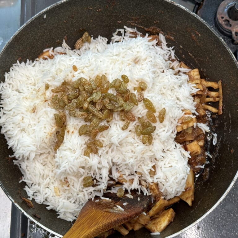 手順 7: レーズンと、茹でた米を加え一緒に炒め合わせ、火を消し蓋をして蒸らす。